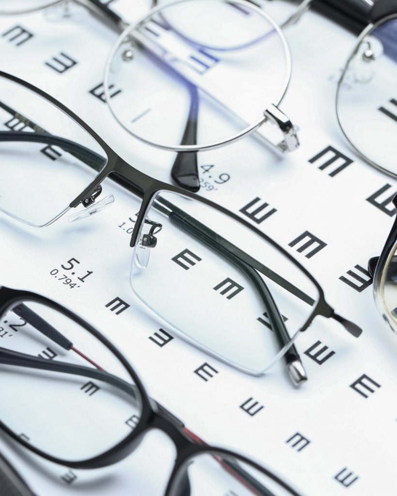 Glasses and eye chart on white background